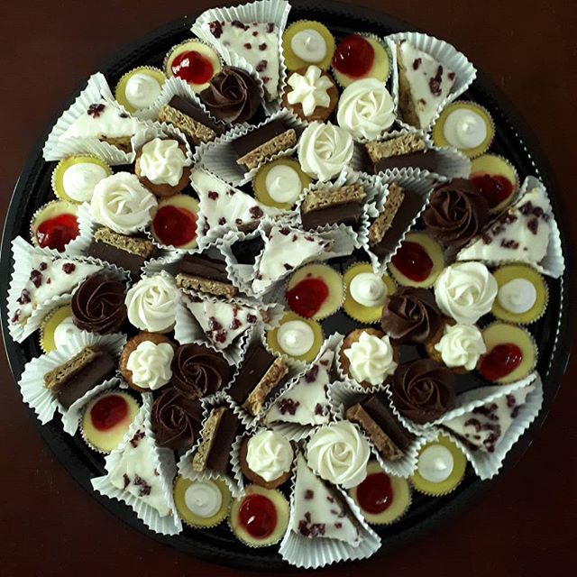 a large assortment of squares, tarts, cookies, and fudge on a platter