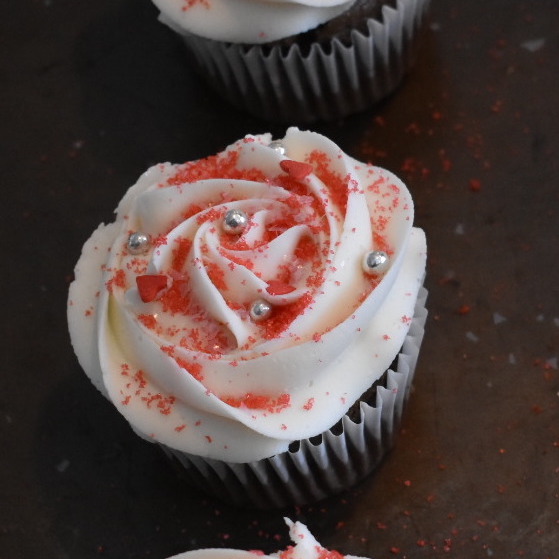 cupcake decorated with white icing and red and silver sprinkles